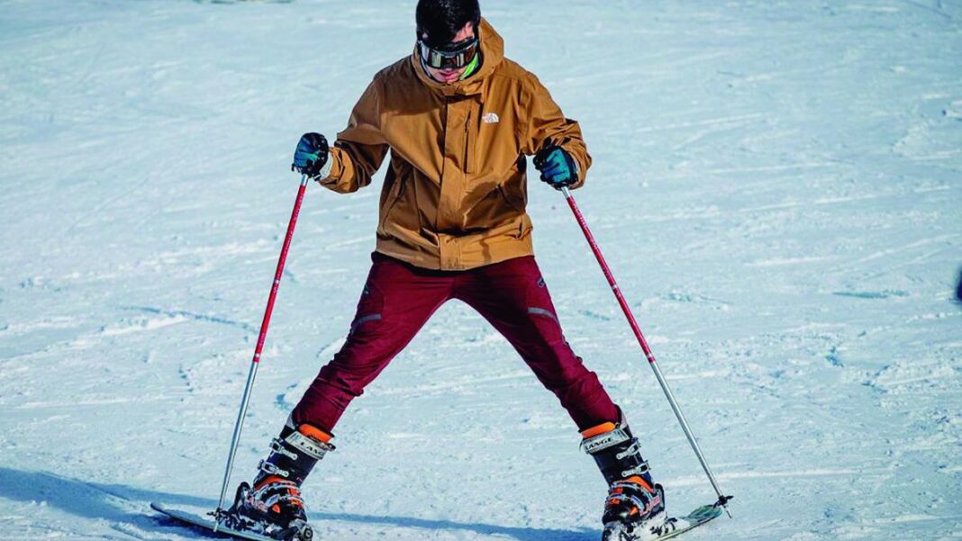 Vista panorámica de Bariloche con montañas nevadas y el lago Nahuel Huapi en primer plano.