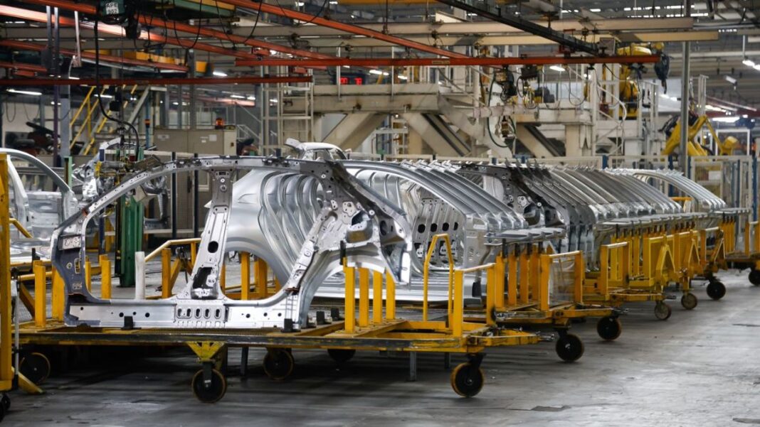 Fachada de una planta industrial con trabajadores en la entrada, representativa del sector manufacturero.